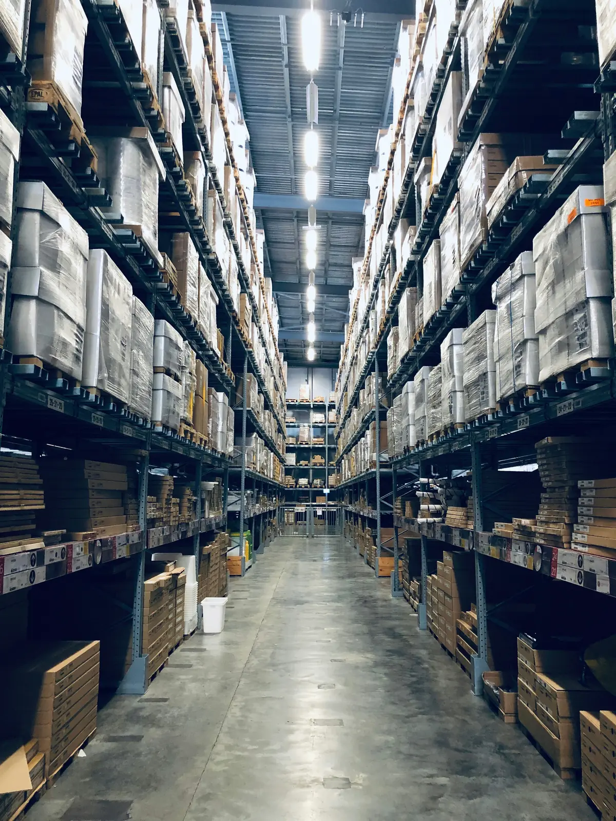 Narrow aisle between tall pallet racking stacked with boxes in a distribution warehouse